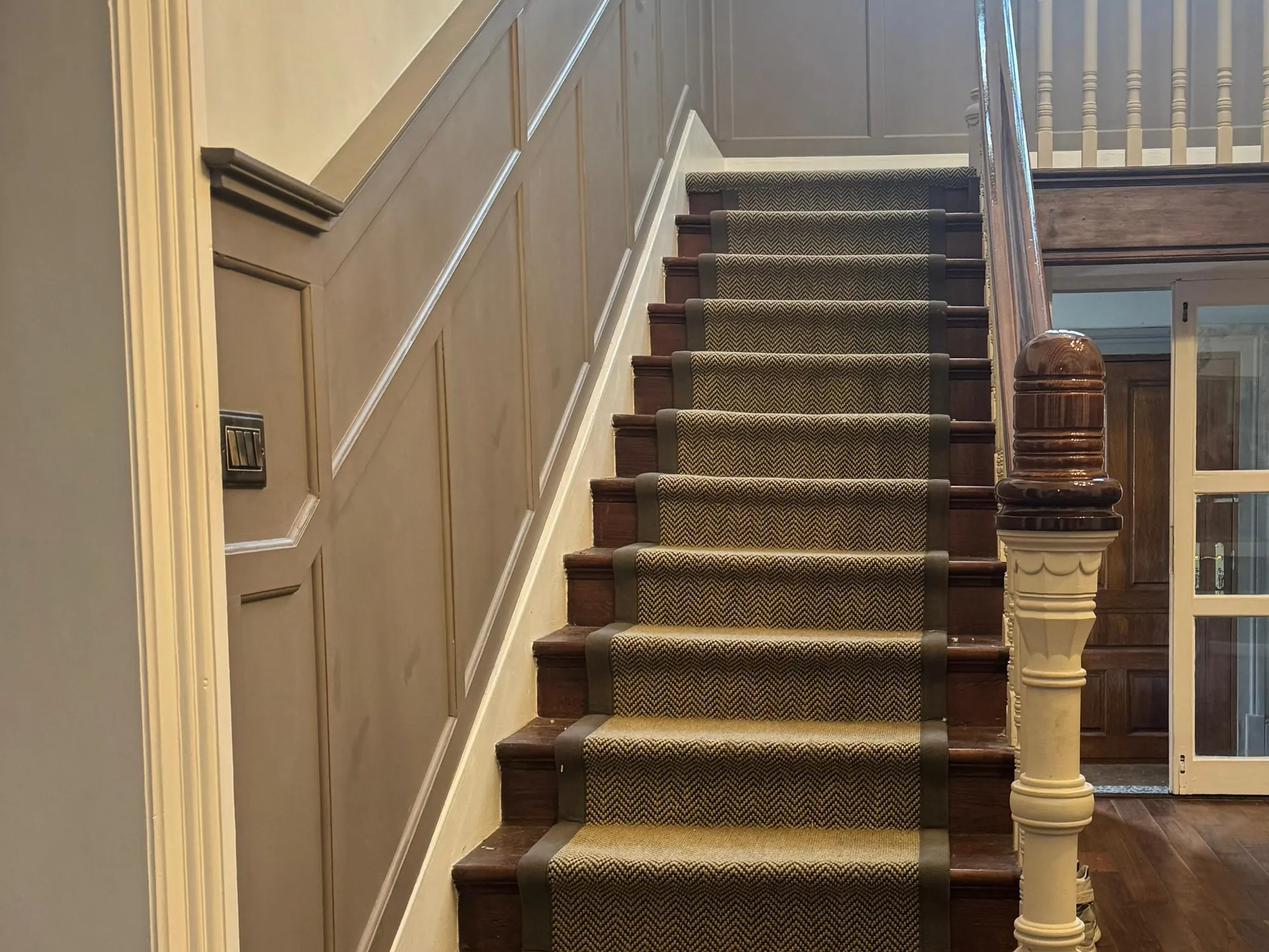 Panelled hallway with a real wood floor and a herringbone stair runner, fitted by SR Carpets & Floors