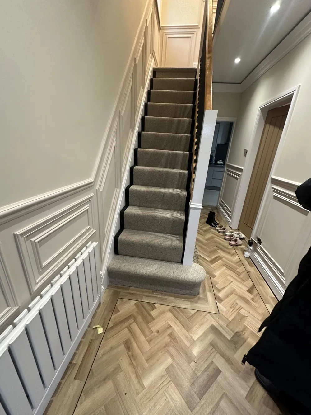 Herringbone LVT hallway with a carpeted staircase