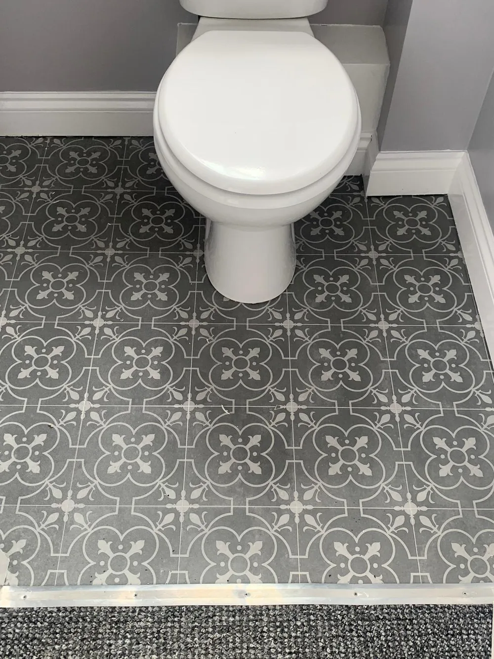 Grey patterned tile-effect vinyl in a cloakroom